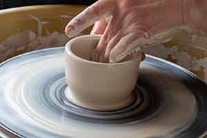 hand moulding clay on a turning table